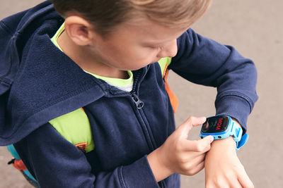 High angle view of boy touching wristwatch