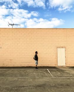 Rear view of woman against wall against sky