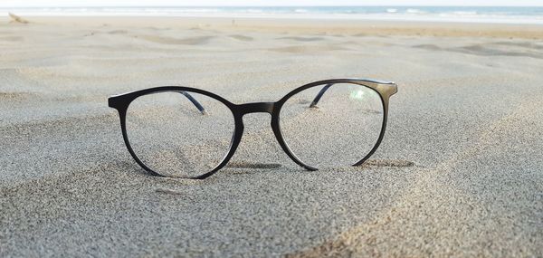 Close-up of eyeglasses on sand at beach