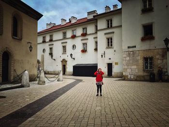 Rear view of woman walking on road against buildings