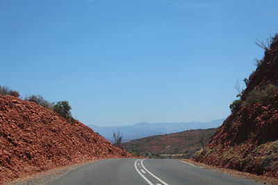 Road by mountain against clear blue sky