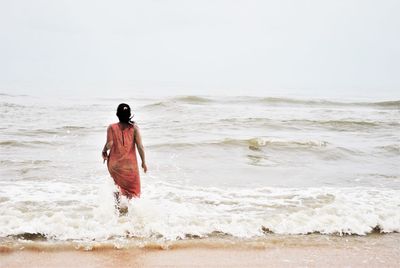 Rear view of man with surfboard walking on beach