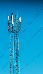 Men on communications tower against clear blue sky