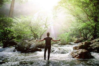 Full length of man standing on rock in forest