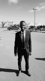 Full length portrait of young man standing at street on sunny day