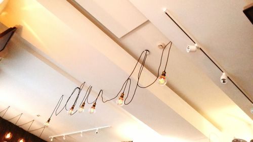 Low angle view of illuminated light bulbs hanging from ceiling