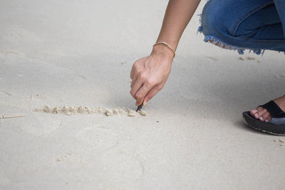 Close-up of woman drawing at beach with stick 