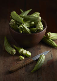 Bowl of okra with knife on cutting board