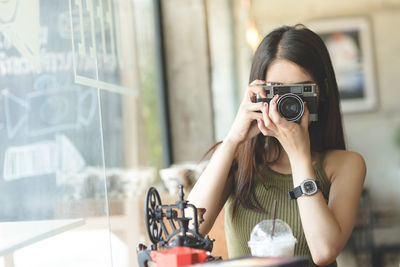 Young woman photographing with camera in cafe