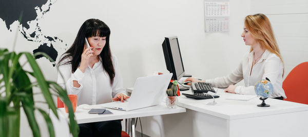 Travel agency working on-line in office, communicating with clients via phone and internet 