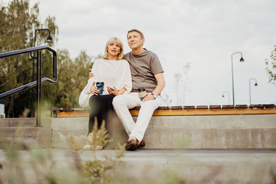 Adult mature happy couple in love sitting on bench outdoors. senior wife and husband romantic date