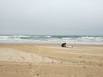 Surfer at beach against sky