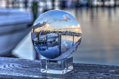 Close-up of crystal ball on glass against water