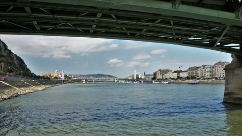 Bridge over river in city against sky