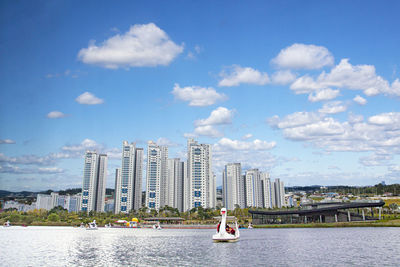 Modern buildings by river against sky in city