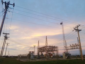 Low angle view of electricity pylon on field against sky