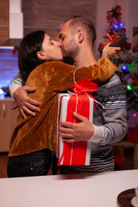 Couple holding box while kissing at home