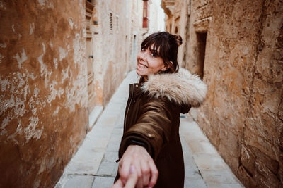 Young woman standing against wall