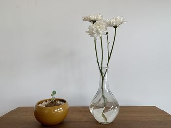 Close-up of white flower vase on table against wall