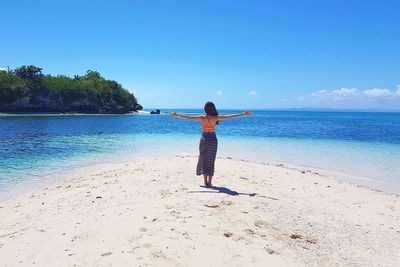 Rear view of woman standing on beach against sky