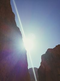 Low angle view of sun shining over mountain