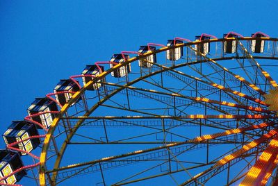 Low angle view of ferris wheel against clear blue sky