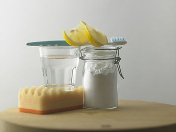 Close-up of baking soda vinegar lemon on table against white background