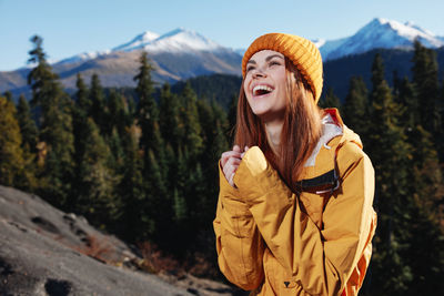 Portrait of young woman standing against mountain