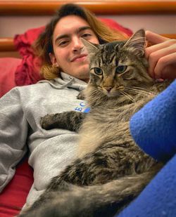 Portrait of young man with cat lying down on sofa