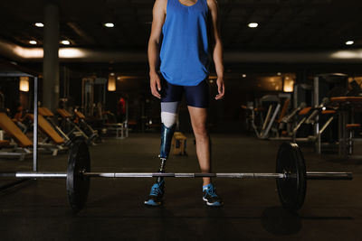 Full length of man with prosthetic legs exercising in gym