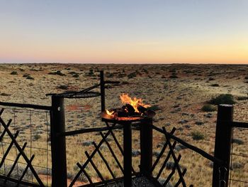 View of bonfire on wooden railing against sky during sunset