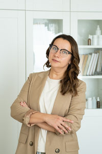 Portrait of young woman standing against wall
