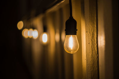 Low angle view of illuminated light bulb hanging on ceiling