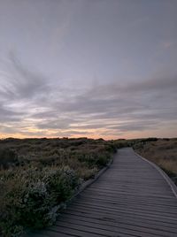 View of boardwalk against sky during sunset