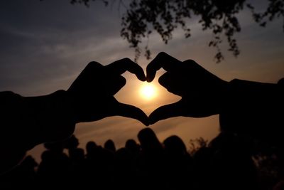 Close-up of silhouette man making heart shape against sky during sunset