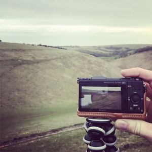 Man photographing camera on landscape against sky