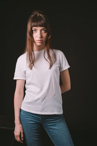 Portrait of beautiful woman standing against black background