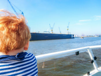 Rear view of boy on sea against sky