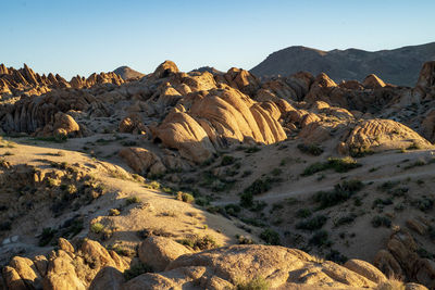 Scenic view of rocky desert against mountains and clear sky