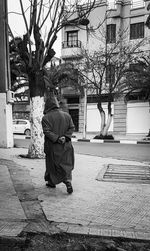 Rear view of man sitting on sidewalk