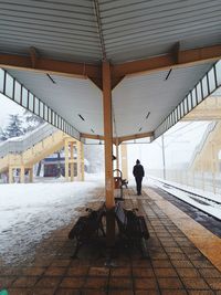 Rear view of man walking at railroad station