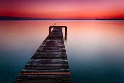 Pier over lake against sky during sunset