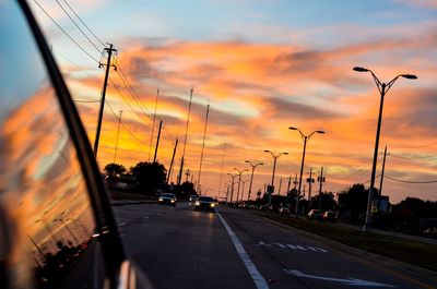 Cars on road in city against sky during sunset