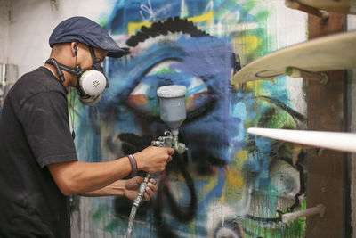 Surfboard shaper workshop, surfshop employee spray painting wall design