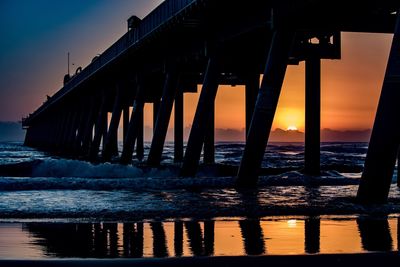 Pier on sea against sky during sunset