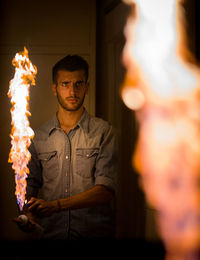 Portrait of young man standing against a mirror with fire