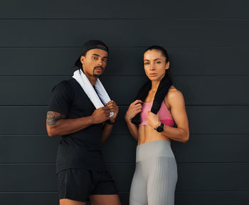 Portrait of smiling couple standing against wall