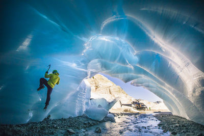 Man ice climbing in cave during luxury adventure tour.