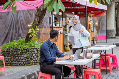 Portrait of young woman using laptop while sitting in cafe