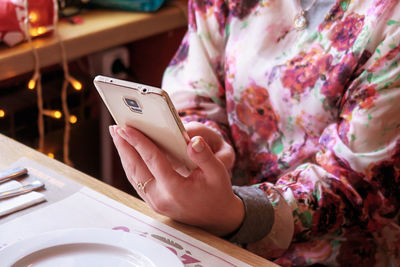 Midsection of woman using mobile phone in restaurant